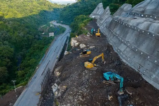 Carretera en construcción junto a un talud y maquinaria pesada
