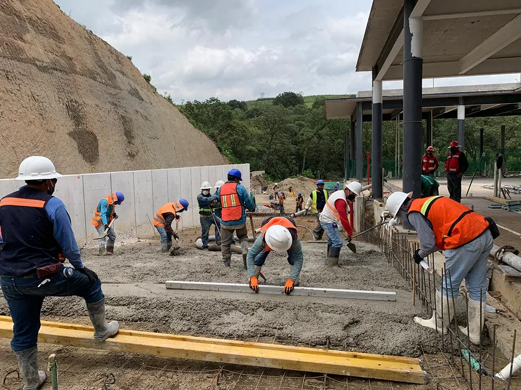 Cuadrilla de trabajadores con equipo de protección colando concreto en obra
