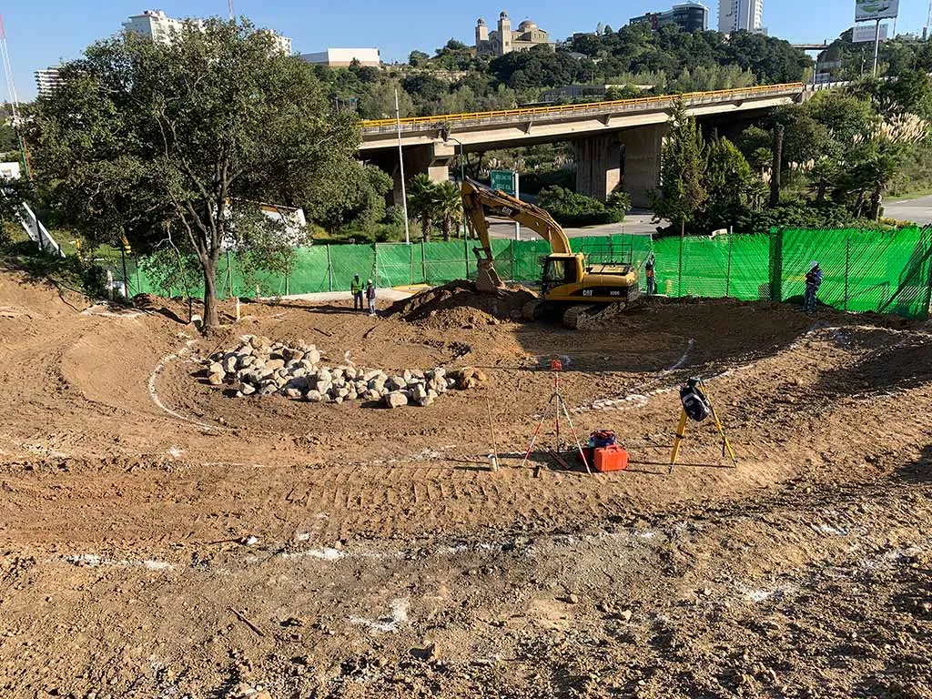 Excavadora y personal topográfico trabajando en una obra de infraestructura